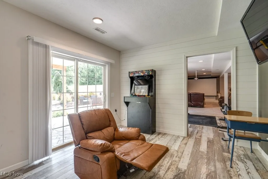 Living area featuring wood-type flooring, wooden walls, and a textured ceiling