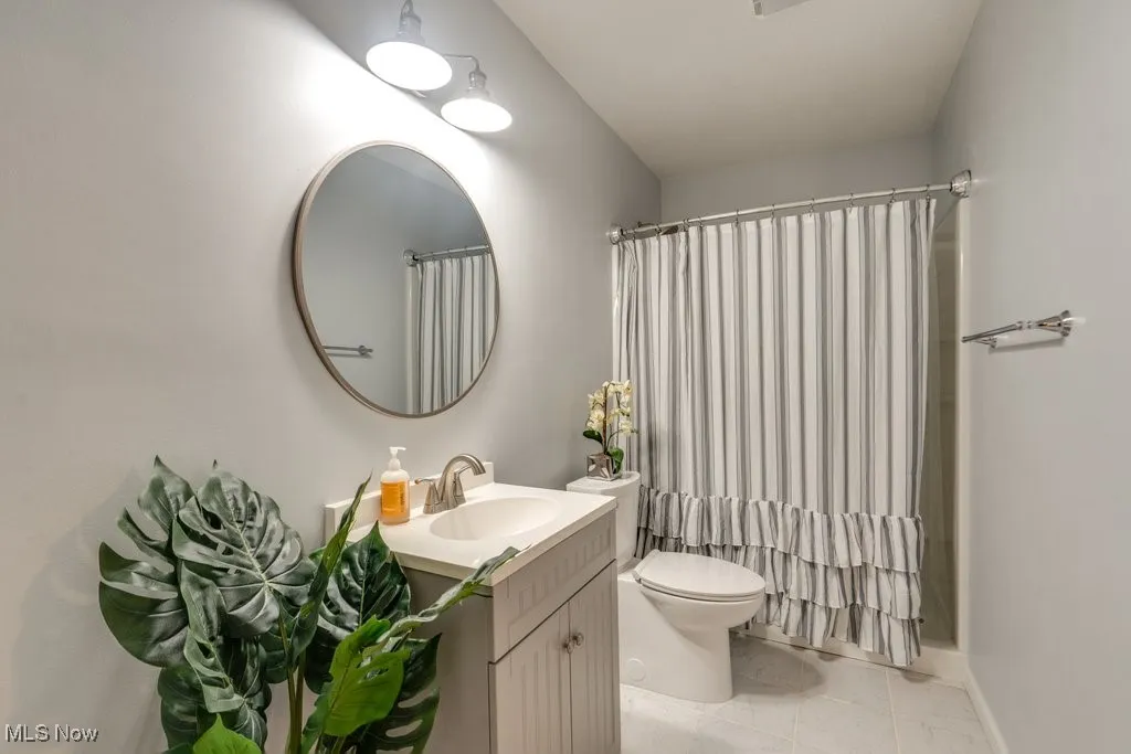 Bathroom with vanity, a shower with shower curtain, and light tile patterned floors