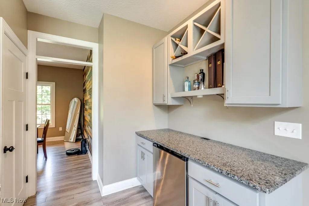 Kitchen with open shelves, light stone countertops, light wood finished floors, white cabinetry, and a textured ceiling