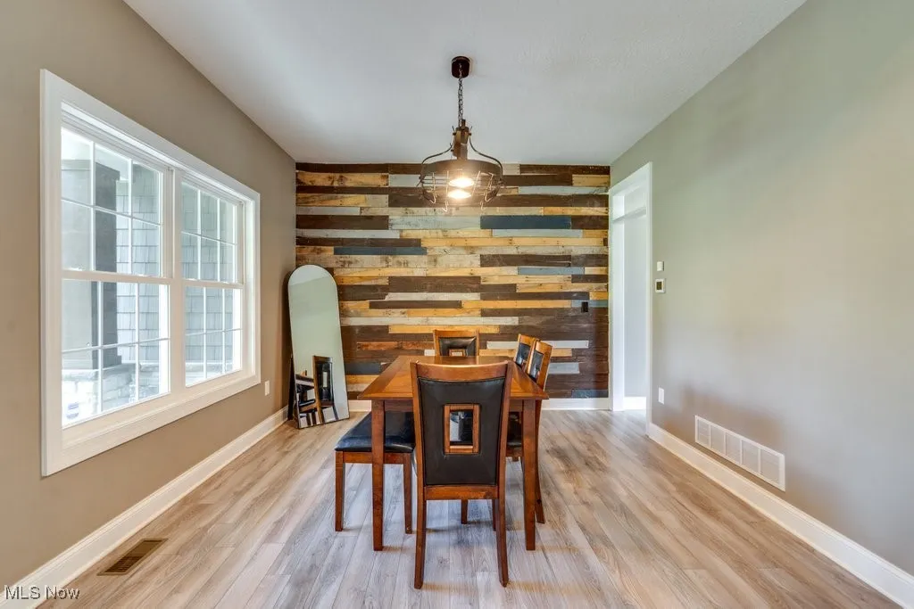 Dining area featuring wood walls, an accent wall, and light wood finished floors