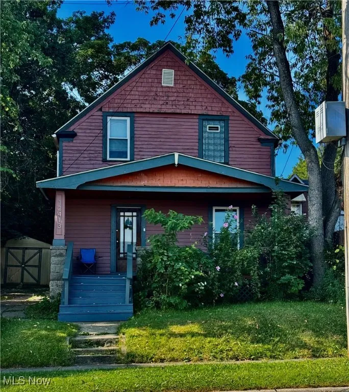American foursquare style home with a storage unit, a front yard, and a porch