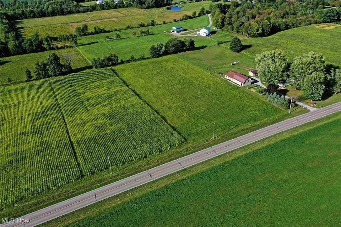 Aerial view of property and surrounding area featuring rural landscape and rows of crops