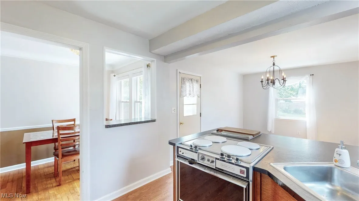 Kitchen featuring light wood-style flooring, electric range, dark countertops, pendant lighting