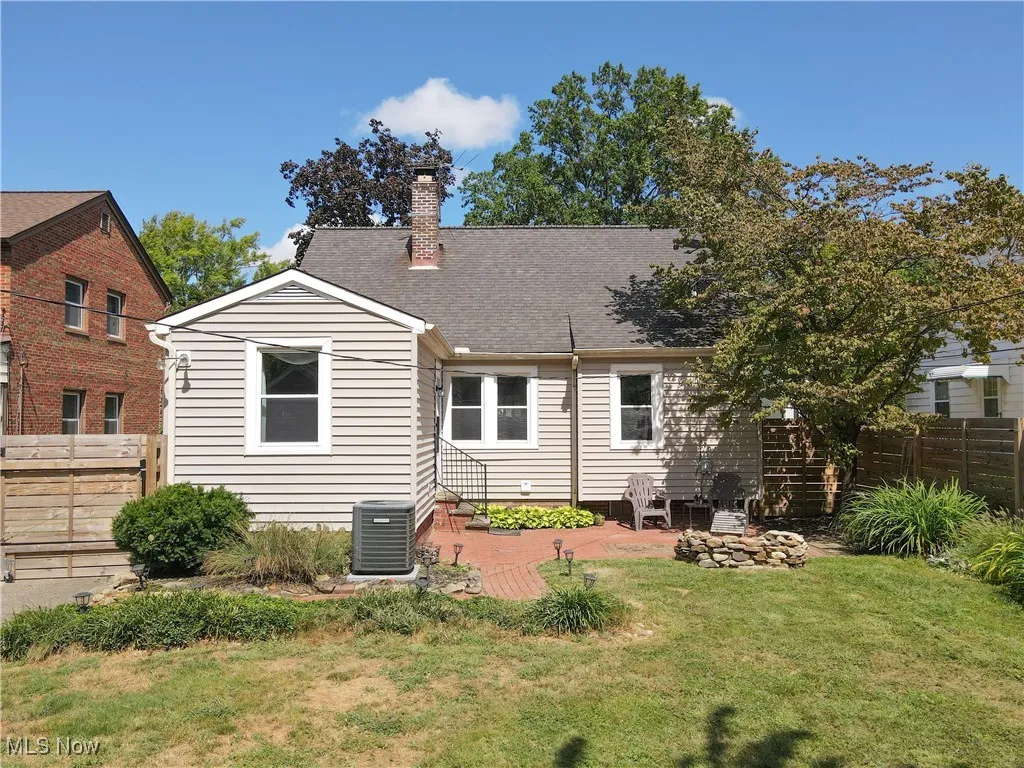 Rear view of property with a fenced backyard, a patio area, a chimney, and roof with shingles
