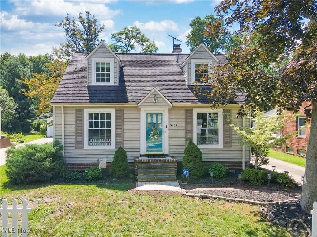 Cape cod home featuring a front yard, a shingled roof, and a chimney