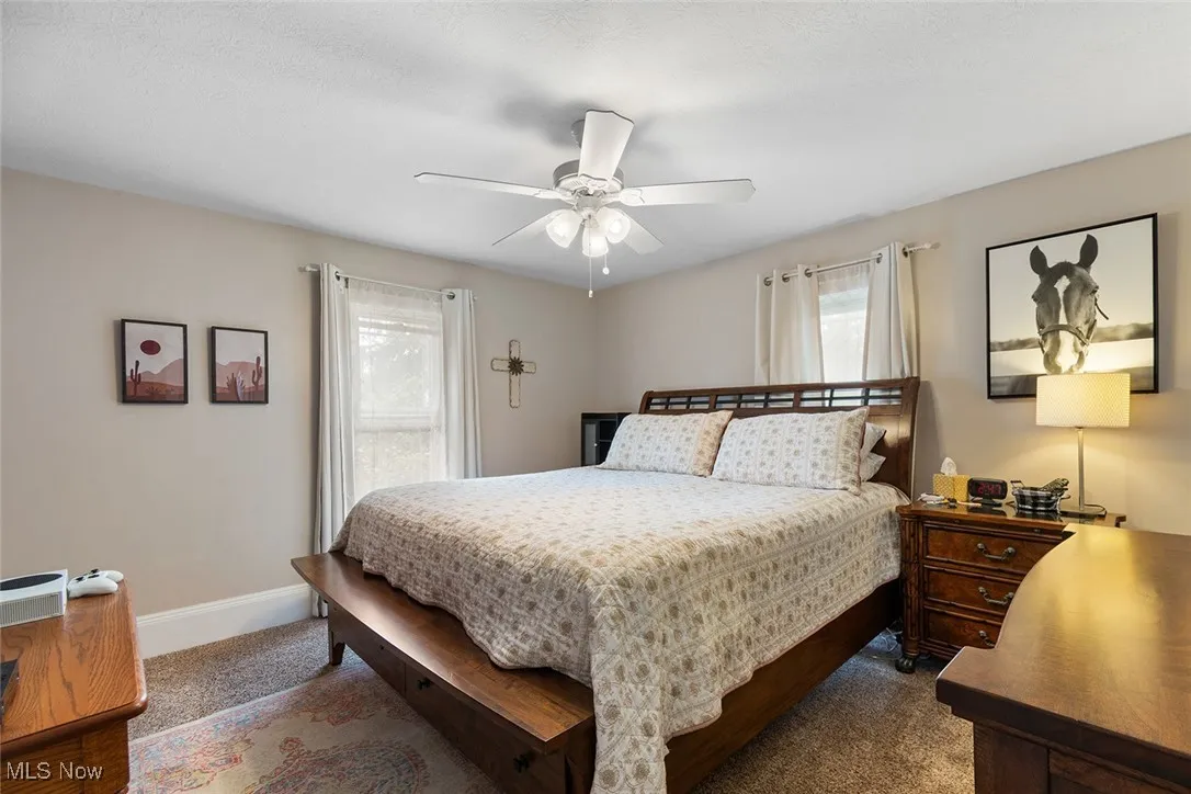 Carpeted bedroom featuring ceiling fan and baseboards