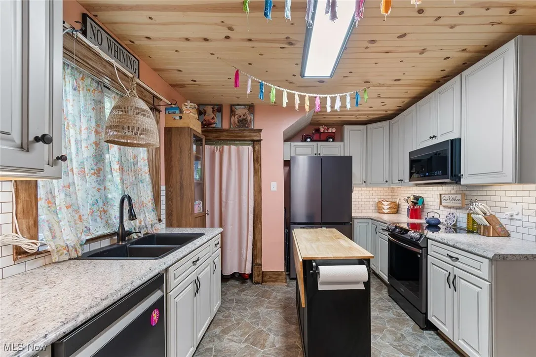 Kitchen with tasteful backsplash, wooden ceiling, butcher block counters, light stone finish floors, and range with electric stovetop