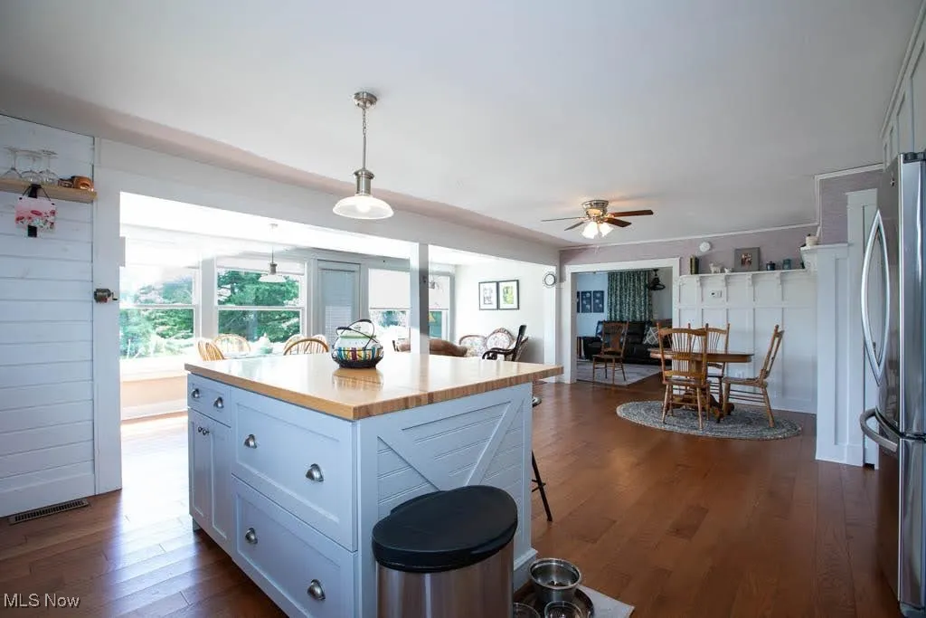 Kitchen with a kitchen bar, decorative light fixtures, dark wood finished floors, freestanding refrigerator, and ceiling fan