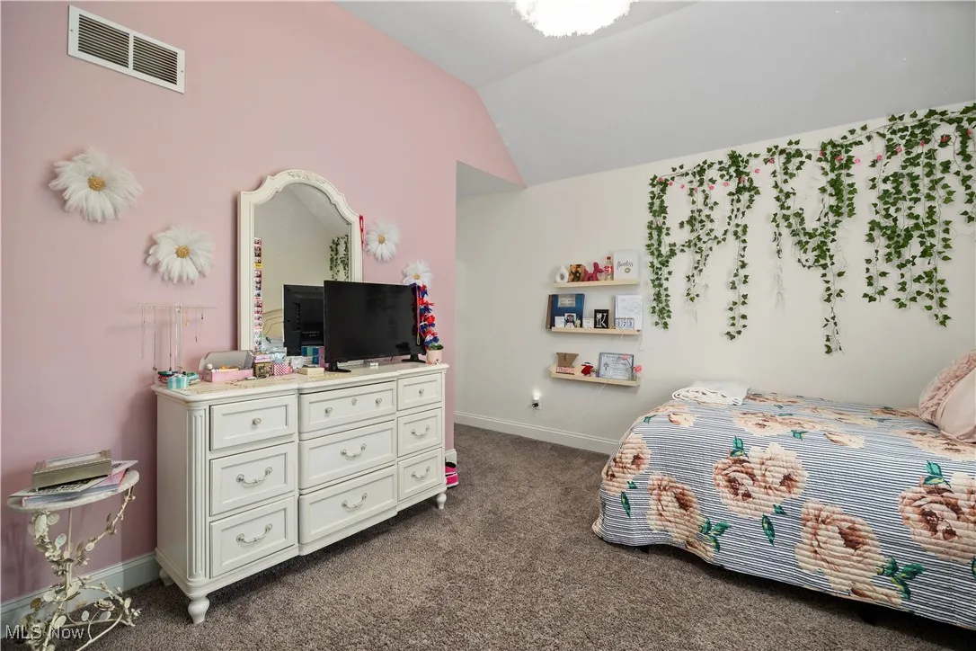 Bedroom featuring dark colored carpet and lofted ceiling