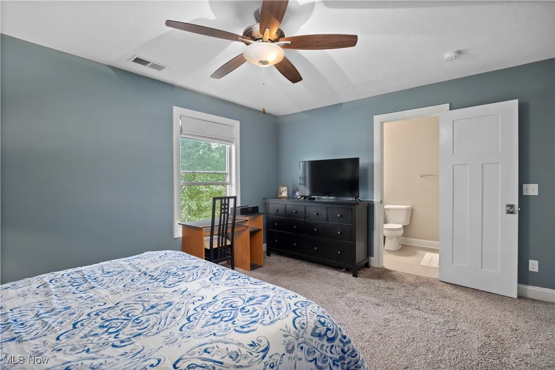 Bedroom with light colored carpet and a ceiling fan