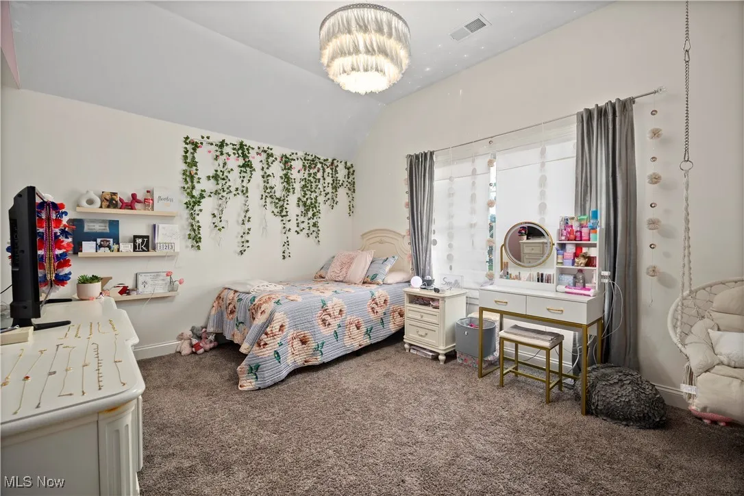 Bedroom with dark carpet, lofted ceiling, and a chandelier