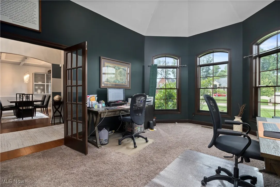 Carpeted home office with plenty of natural light, french doors, and high vaulted ceiling