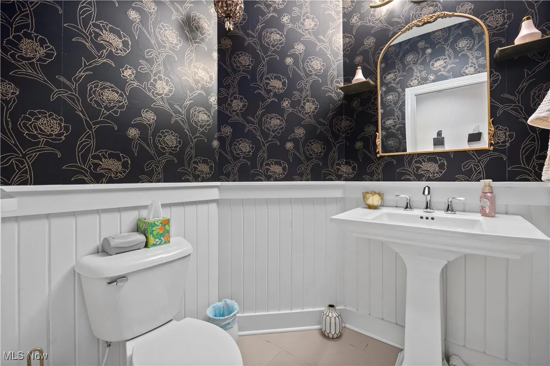 Bathroom with wallpapered walls and a wainscoted wall