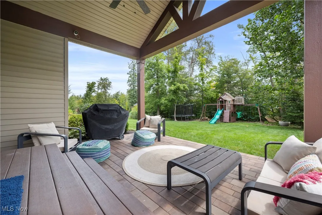 Deck with a playground, a trampoline, a lawn, an outdoor living space, and a grill