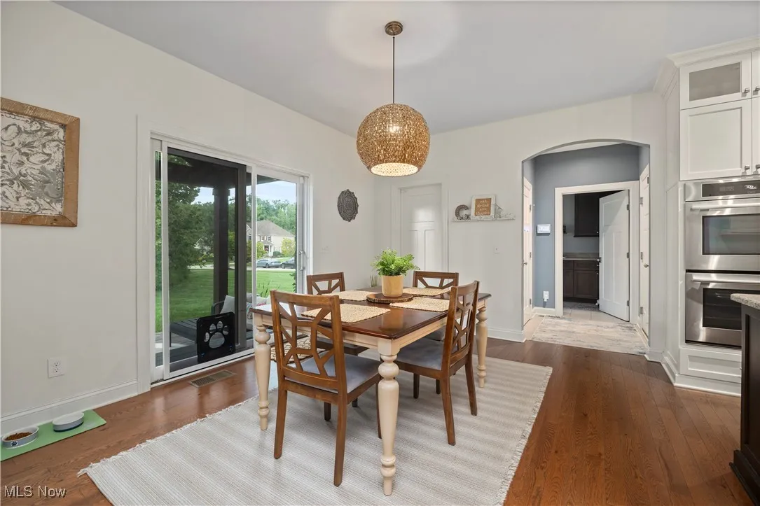 Dining area with arched walkways and dark wood finished floors