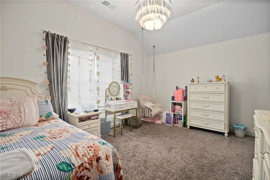 Bedroom with carpet, vaulted ceiling, and a chandelier