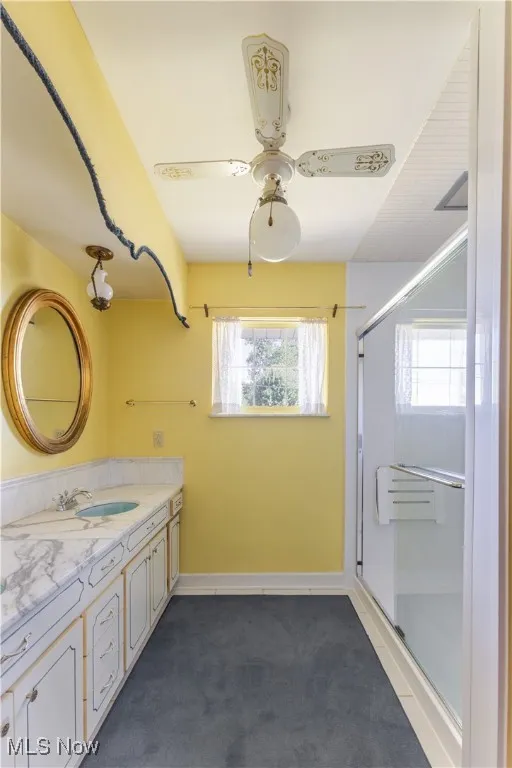 Bathroom featuring a stall shower, vanity, and a ceiling fan