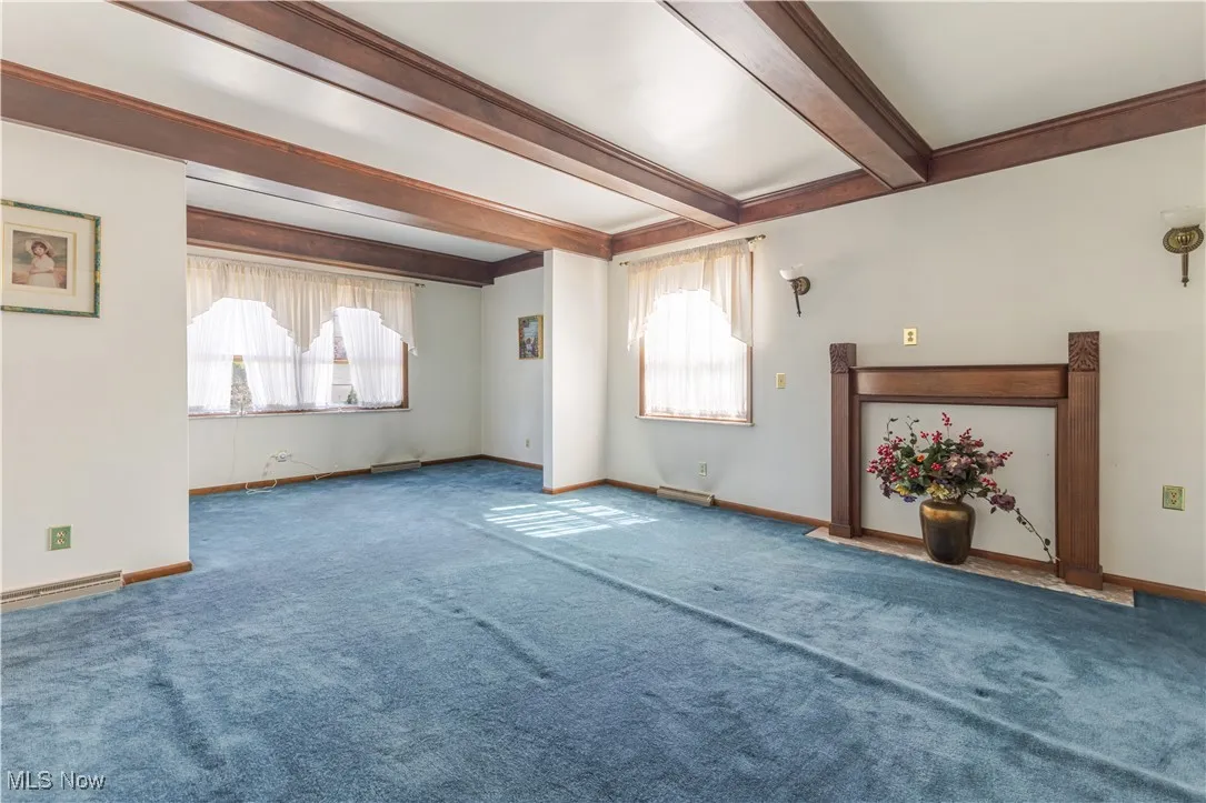 Unfurnished living room with beam ceiling and carpet floors
