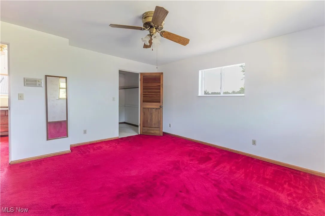 Unfurnished bedroom with a walk in closet, ceiling fan, and carpet flooring