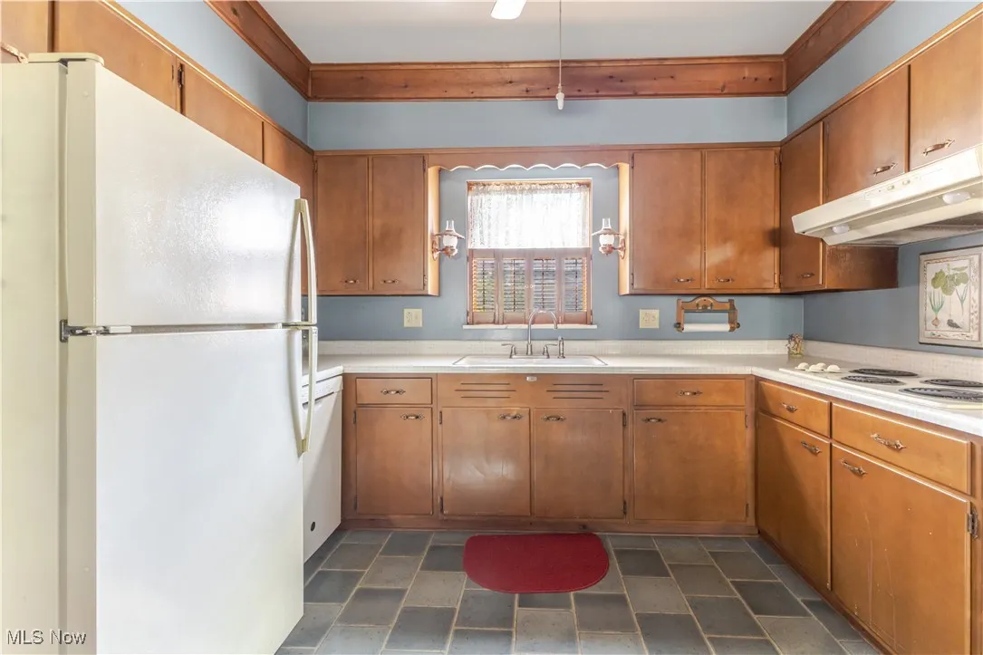 Kitchen with white appliances, light countertops, and brown cabinets