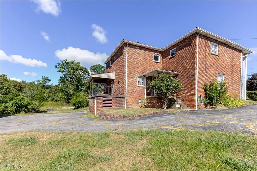 View of home's exterior featuring brick siding, stairway, and a lawn