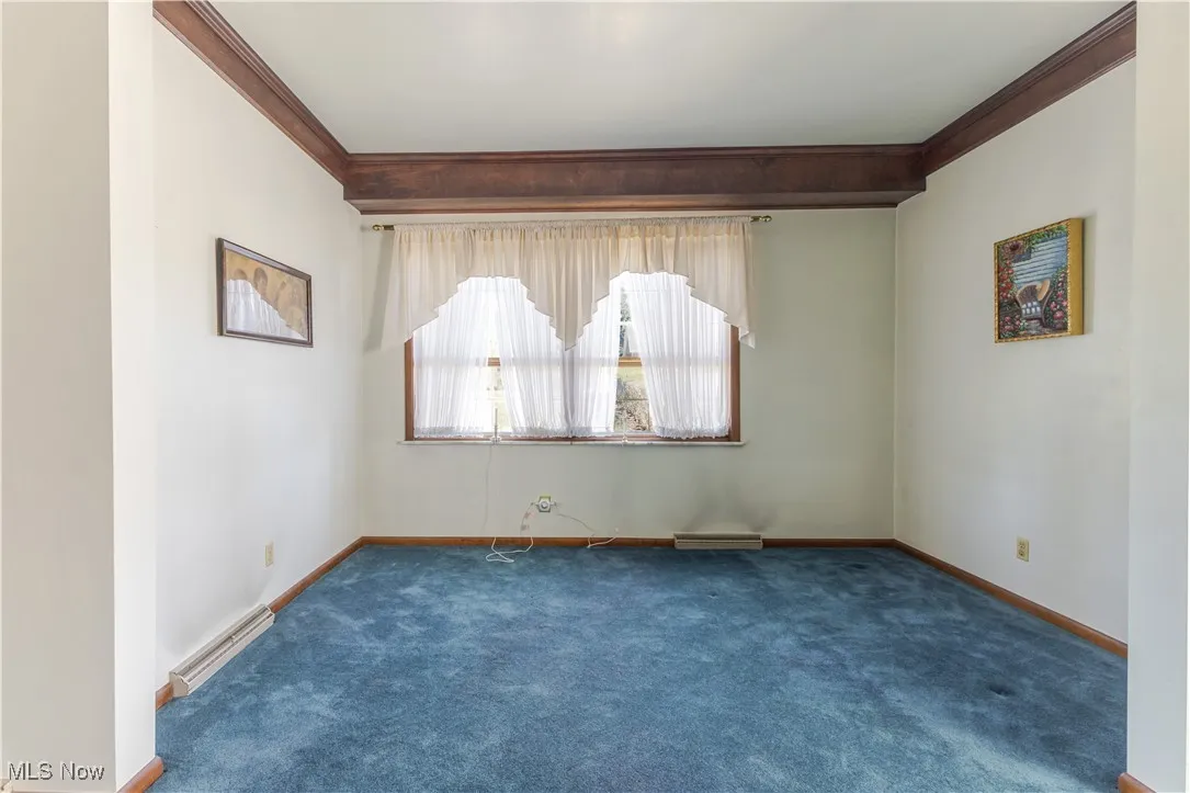 Carpeted empty room featuring ornamental molding and a baseboard radiator