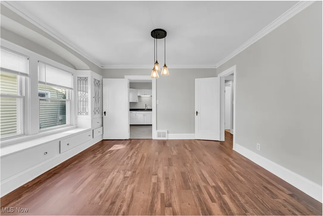 Unfurnished dining area with ornamental molding, dark wood-style flooring, and a chandelier