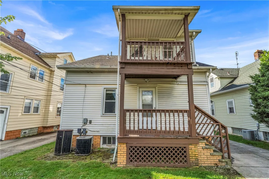 Rear view of house with a balcony, a deck, and a lawn