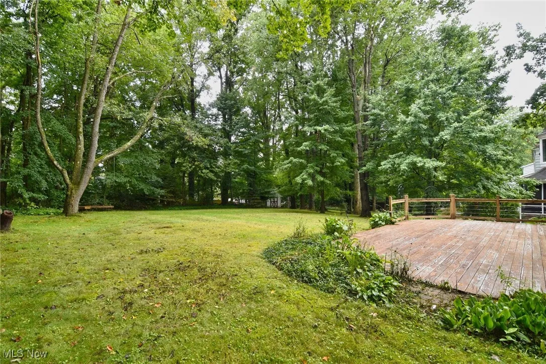 Backyard View of green lawn with a deck and view of scattered trees