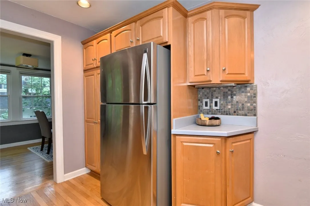 Kitchen with freestanding refrigerator, backsplash, light wood-style flooring, and recessed lighting