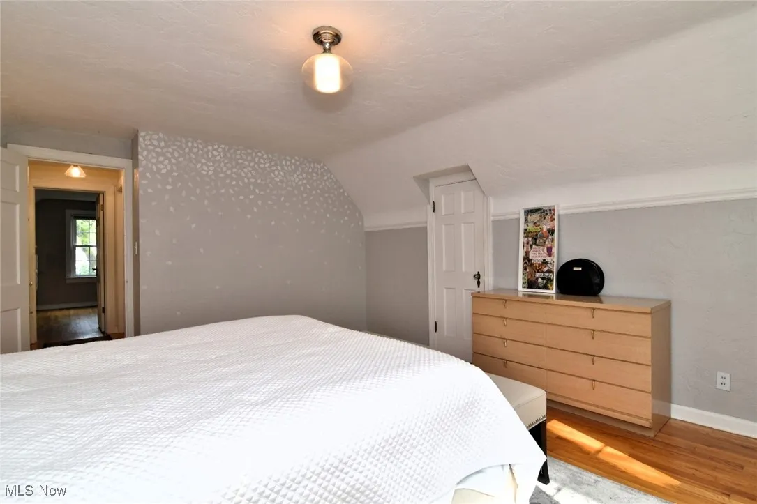 Bedroom with wood finished floors, vaulted ceiling, and a textured ceiling