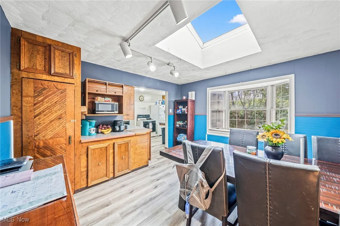 Kitchen with brown cabinets, a skylight, light wood-style floors, light countertops, and rail lighting