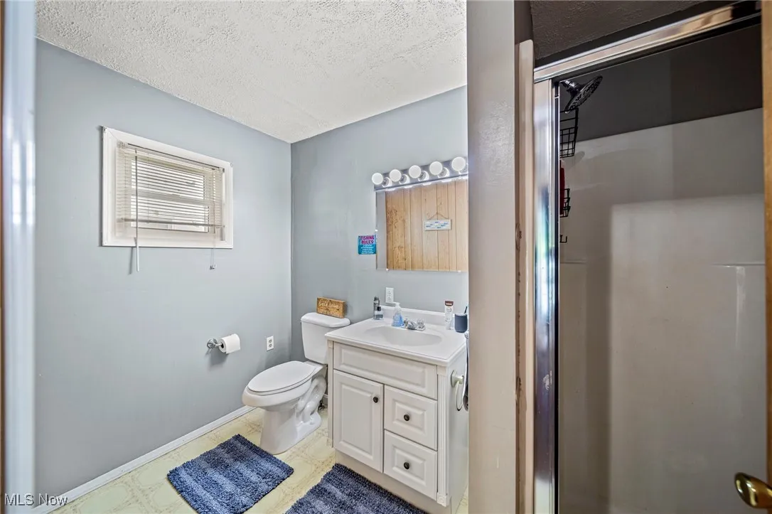 Full bath with vanity, a textured ceiling, and a shower stall