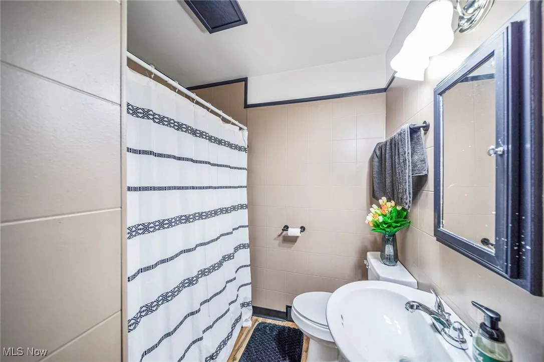 Bathroom with tile walls and a shower with curtain