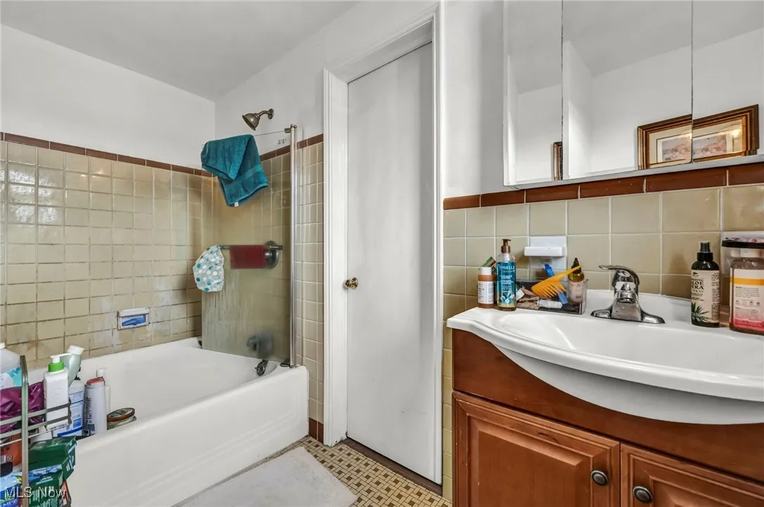 Full bath with vanity, tub / shower combination, and tile walls