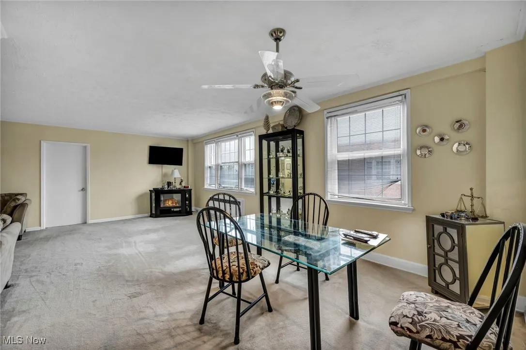 Carpeted dining room with baseboards and a ceiling fan