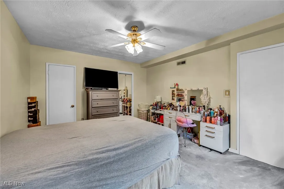 Bedroom featuring carpet, a textured ceiling, ceiling fan, and a closet