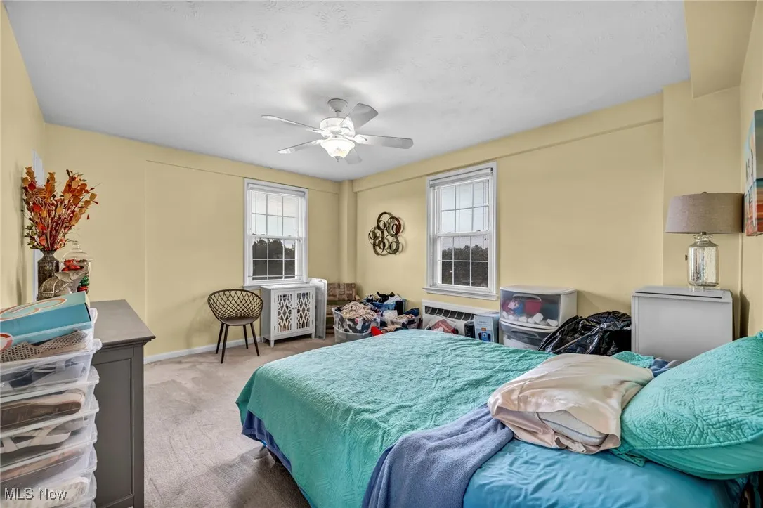 Bedroom with ceiling fan, carpet, a textured ceiling, and radiator