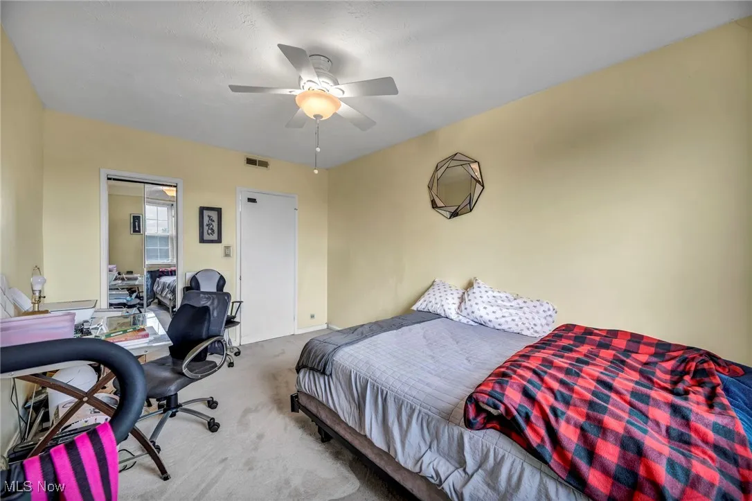 Carpeted bedroom with a desk and a ceiling fan
