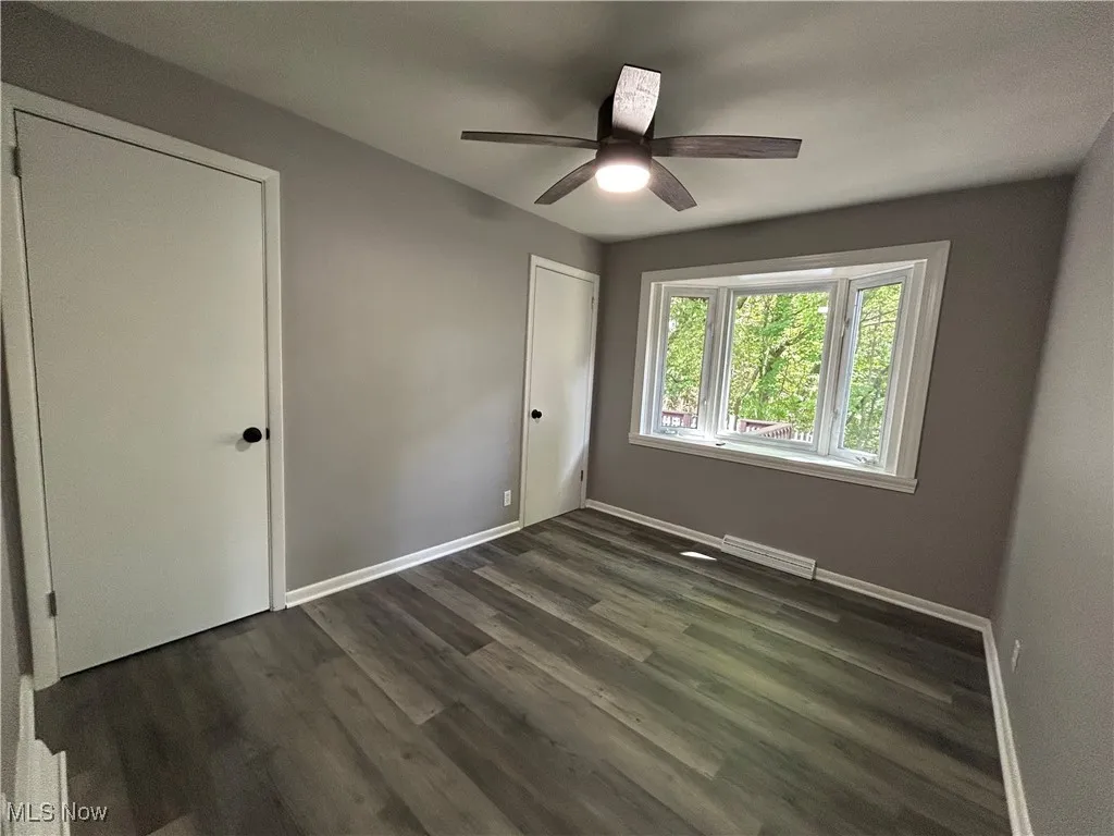 Unfurnished bedroom featuring dark wood-type flooring and a ceiling fan