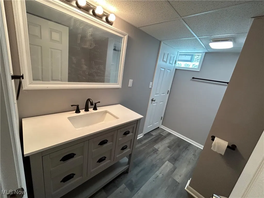 Bathroom with vanity, dark wood-type flooring, and a drop ceiling