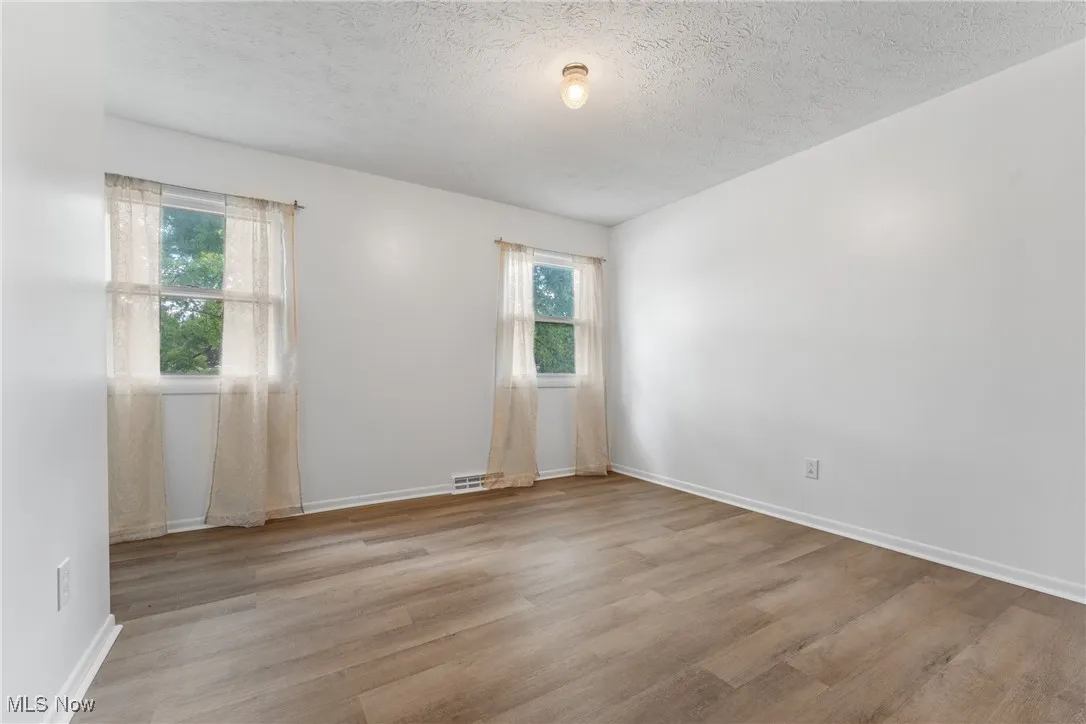 Unfurnished room with light wood-style floors and a textured ceiling