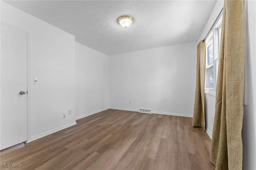 Empty room featuring wood finished floors and a textured ceiling