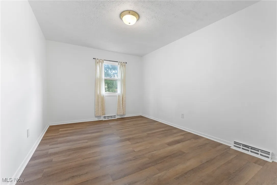 Empty room featuring dark wood-style flooring and a textured ceiling