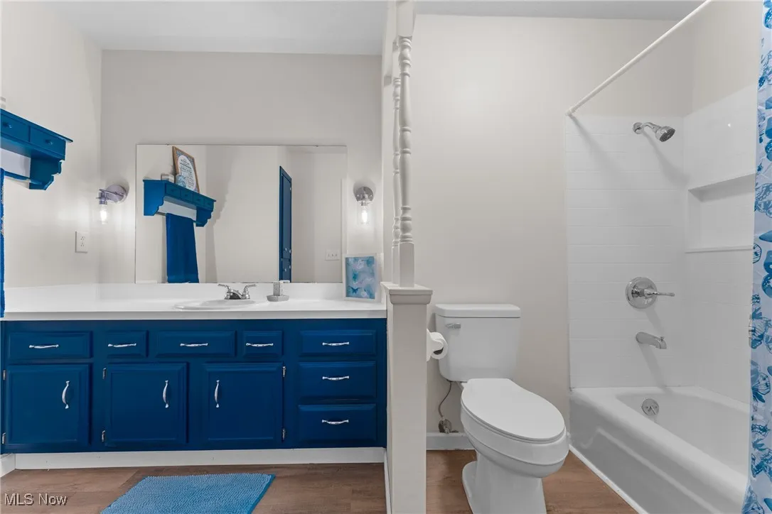 Bathroom featuring shower / bath combo, vanity, and wood finished floors