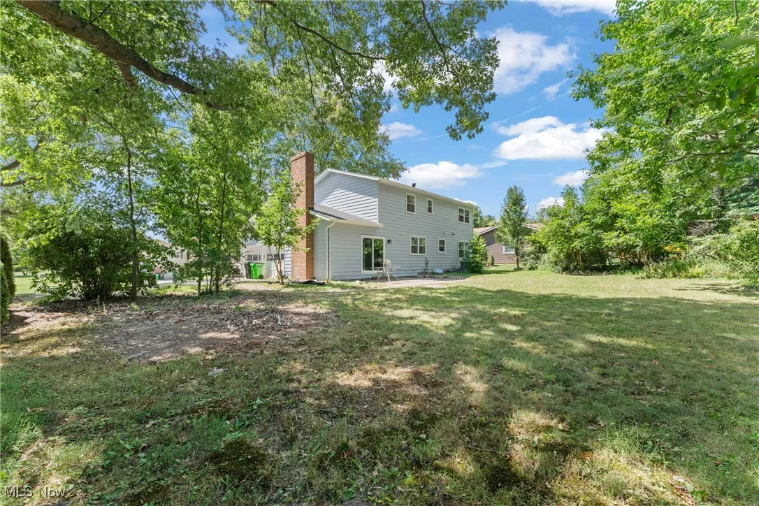 Rear view of house with a chimney, a patio, and a yard