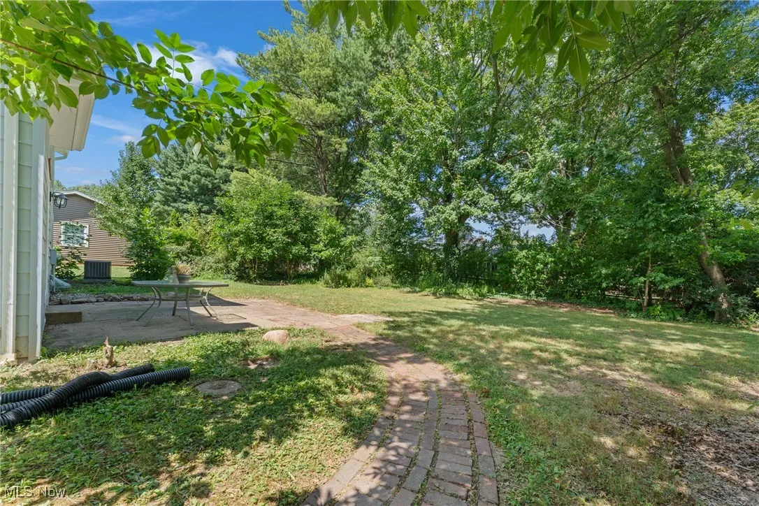 View of grassy yard with a patio area