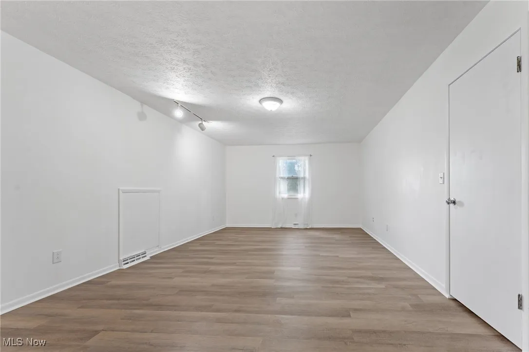 Unfurnished room with a textured ceiling and light wood-type flooring