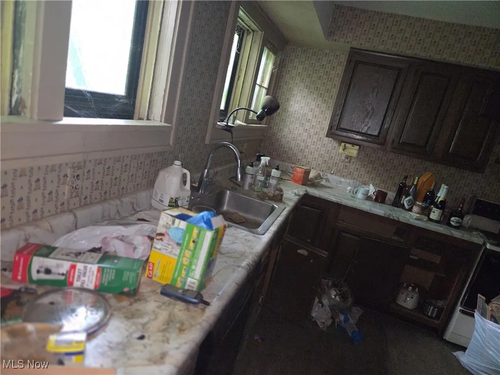 Kitchen featuring dark brown cabinetry and wallpapered walls
