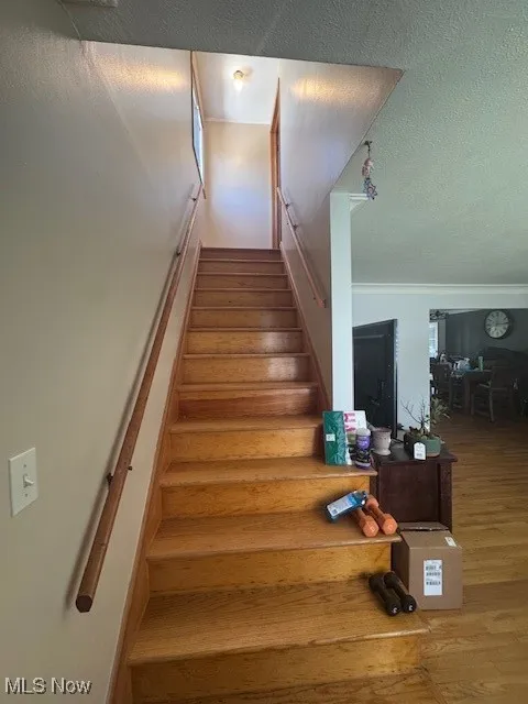 Staircase featuring a textured ceiling and wood finished floors
